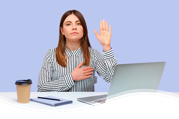 mujer frente a computadora levantando la mano izquierda y colocando su mano derecha sobre el pecho
